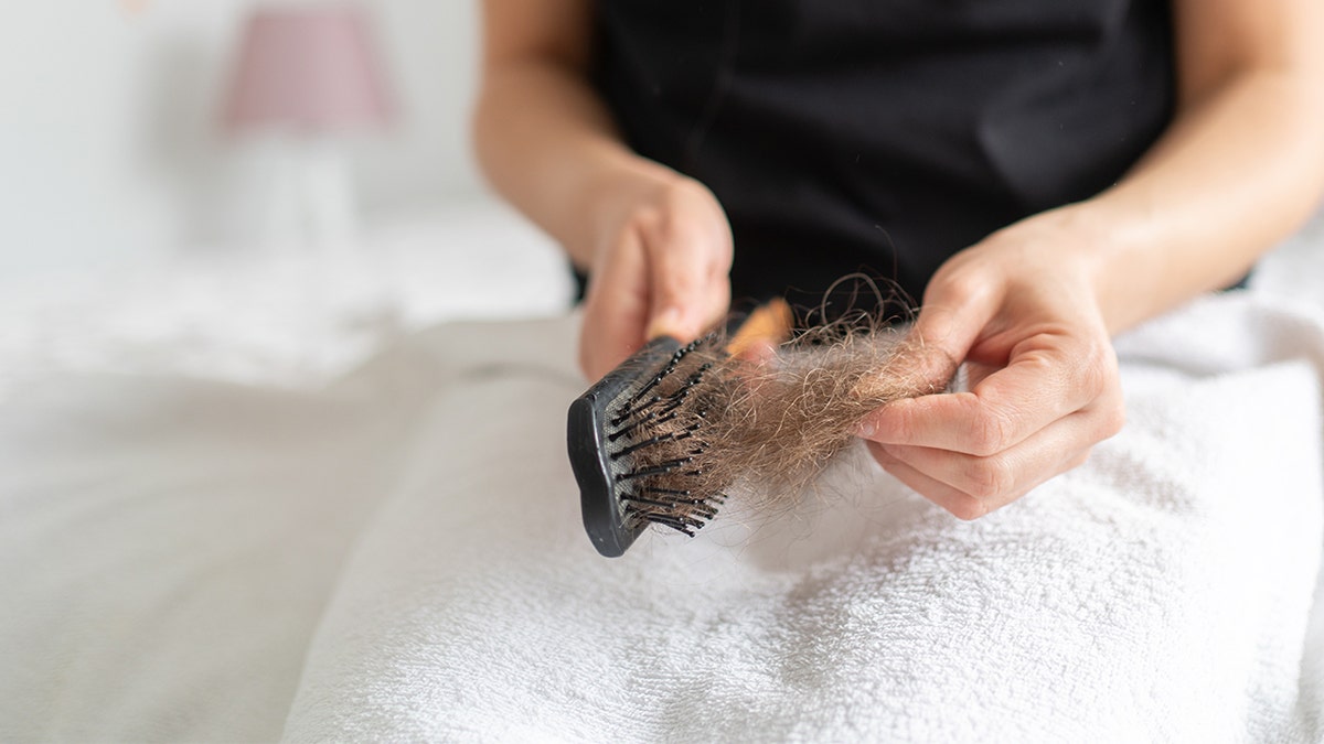 The woman removes her hair from the brush